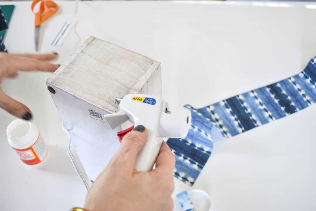 use a combination of hot glue and mod podge to adhere fabric to planter