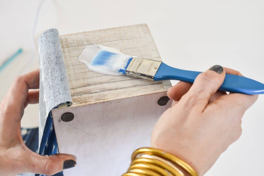 use a combination of hot glue and mod podge to adhere fabric to planter