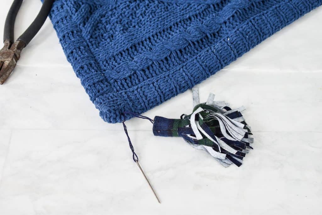 sew the tassel onto the blanket with embroidery thread